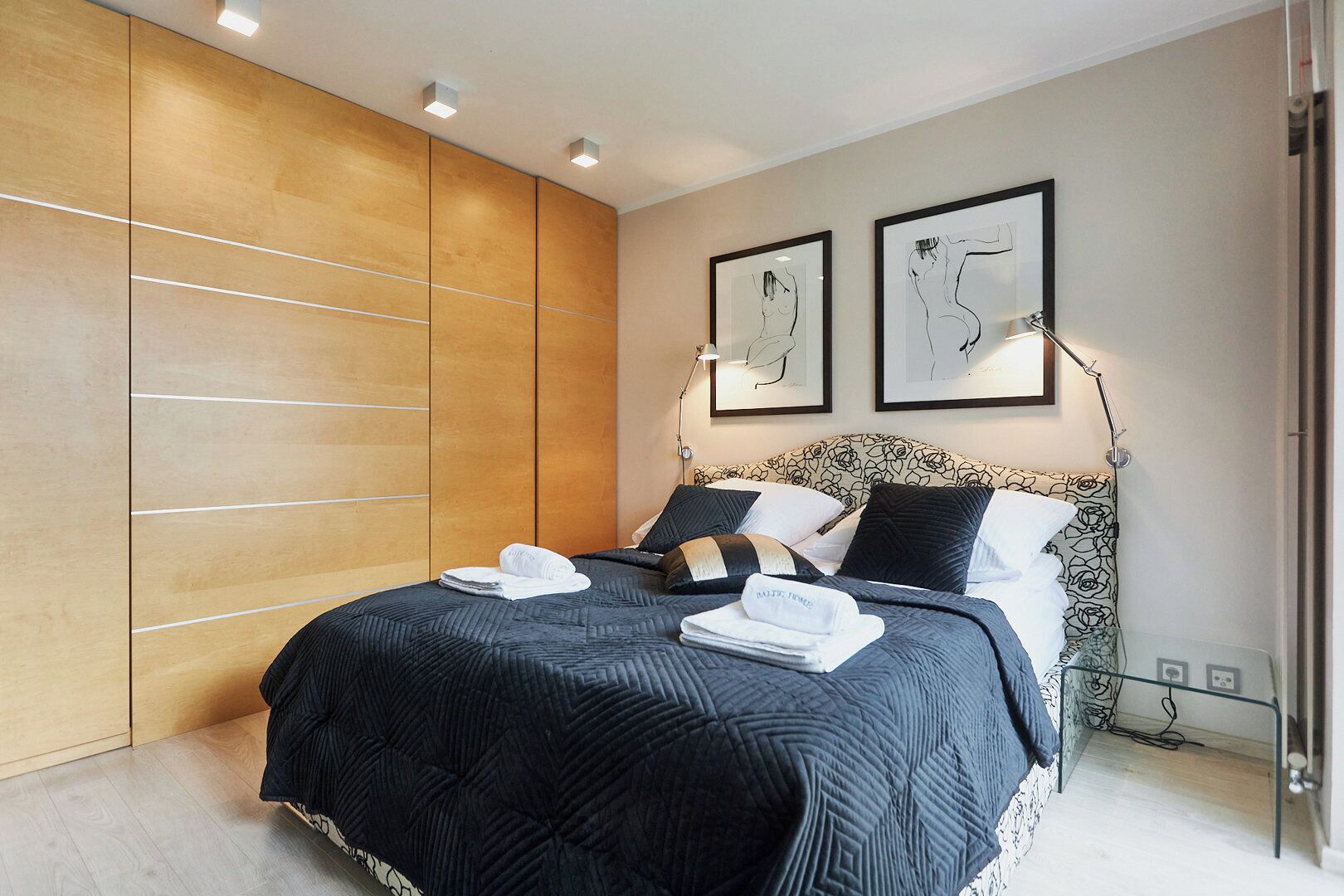 Un dormitorio moderno con una cama grande, un armario de madera y dos cuadros enmarcados en la pared.