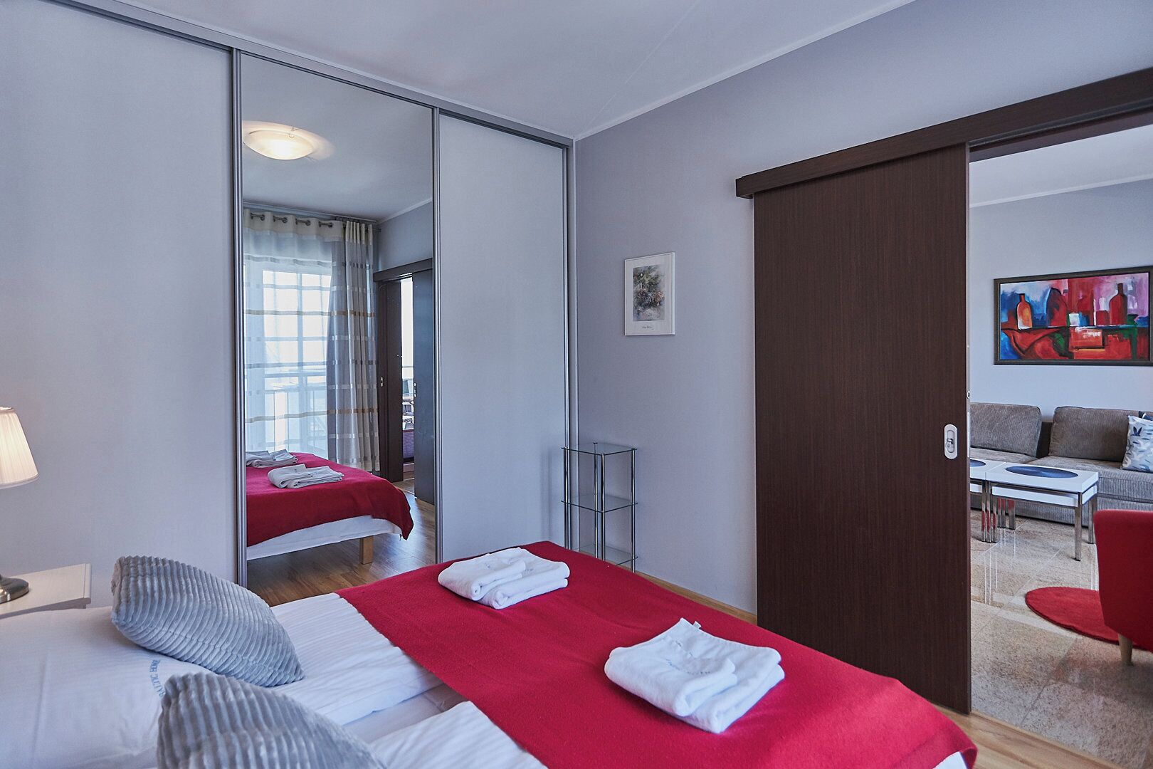 A hotel room with a bed, a mirror, a wardrobe, a small table, and a sofa.