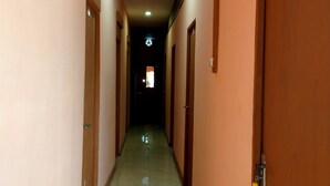 A corridor with doors on both sides, a tiled floor, and a ceiling light. - Hotel Mitra Kapuas Raya Sintang (Sintang)