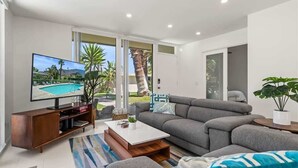 Ein modernes Wohnzimmer mit Flachbildfernseher, grauem Sofa und Couchtisch.