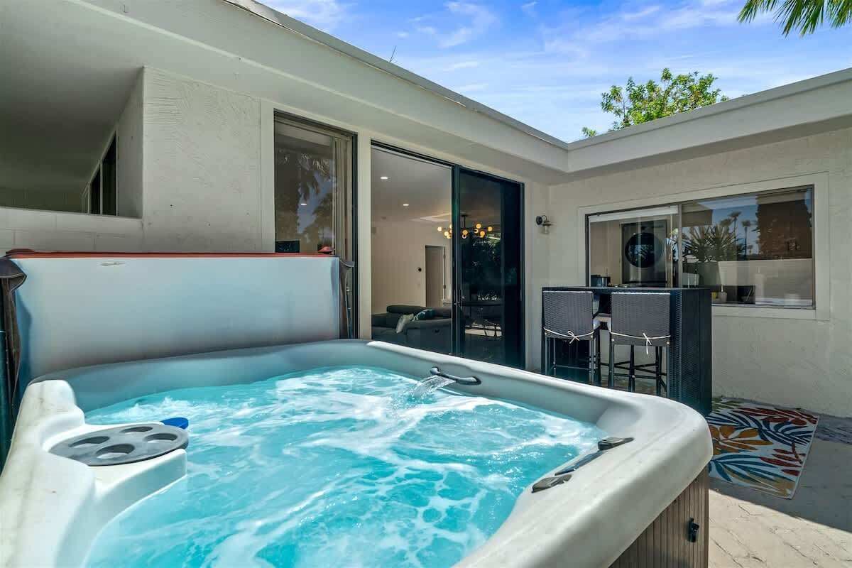 Ein Whirlpool in einem Außenbereich mit einer Terrassentür, die zu einem Innenraum führt.