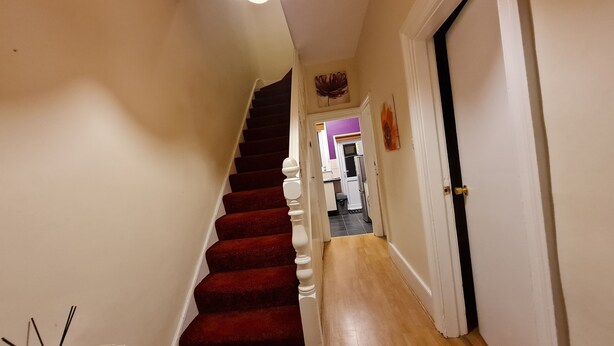 A staircase with red carpet leading to a room with a white door. - House-sleeps4-parking-garden (London)