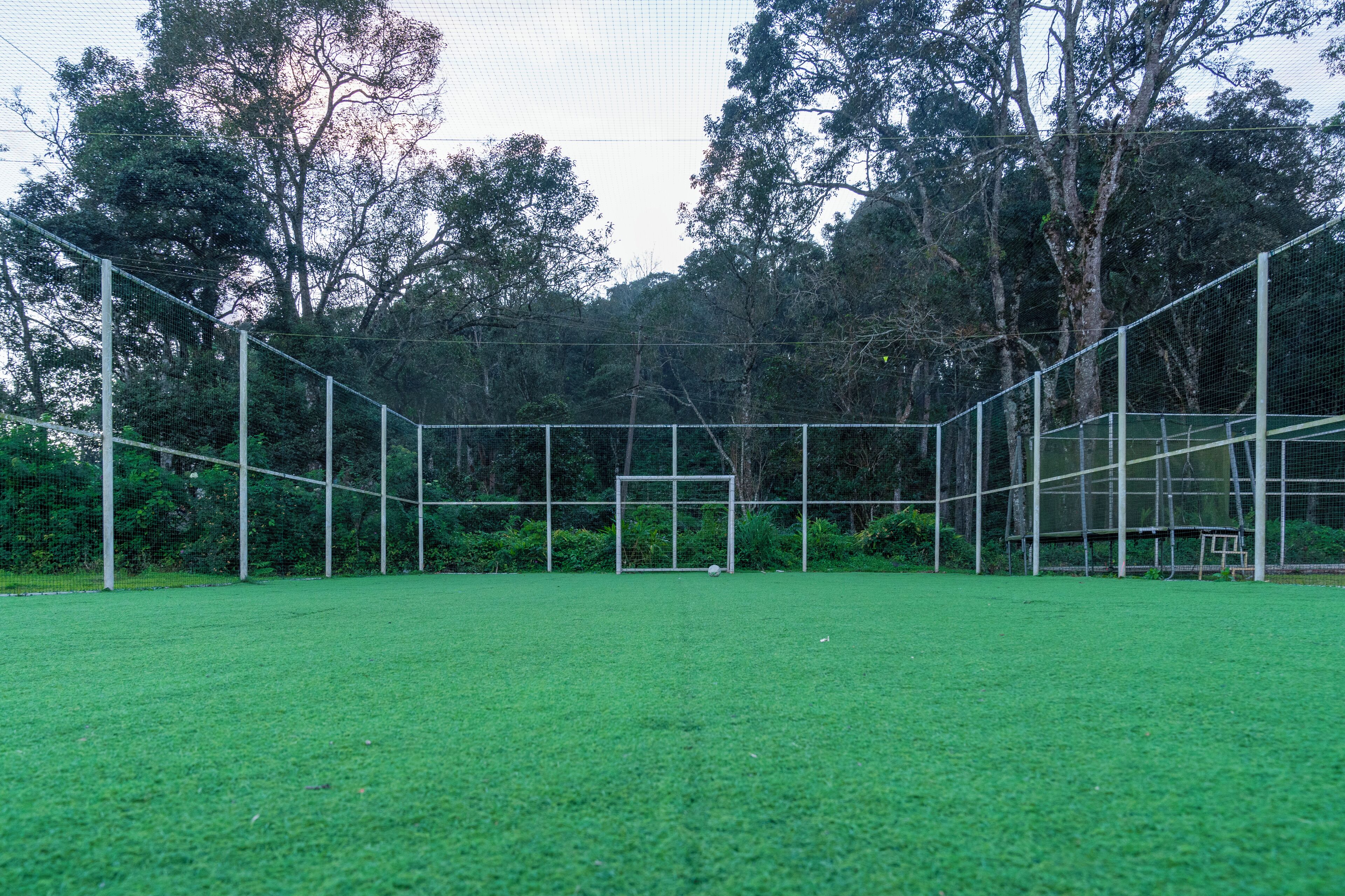 A fenced sports field with a goalpost and a net.