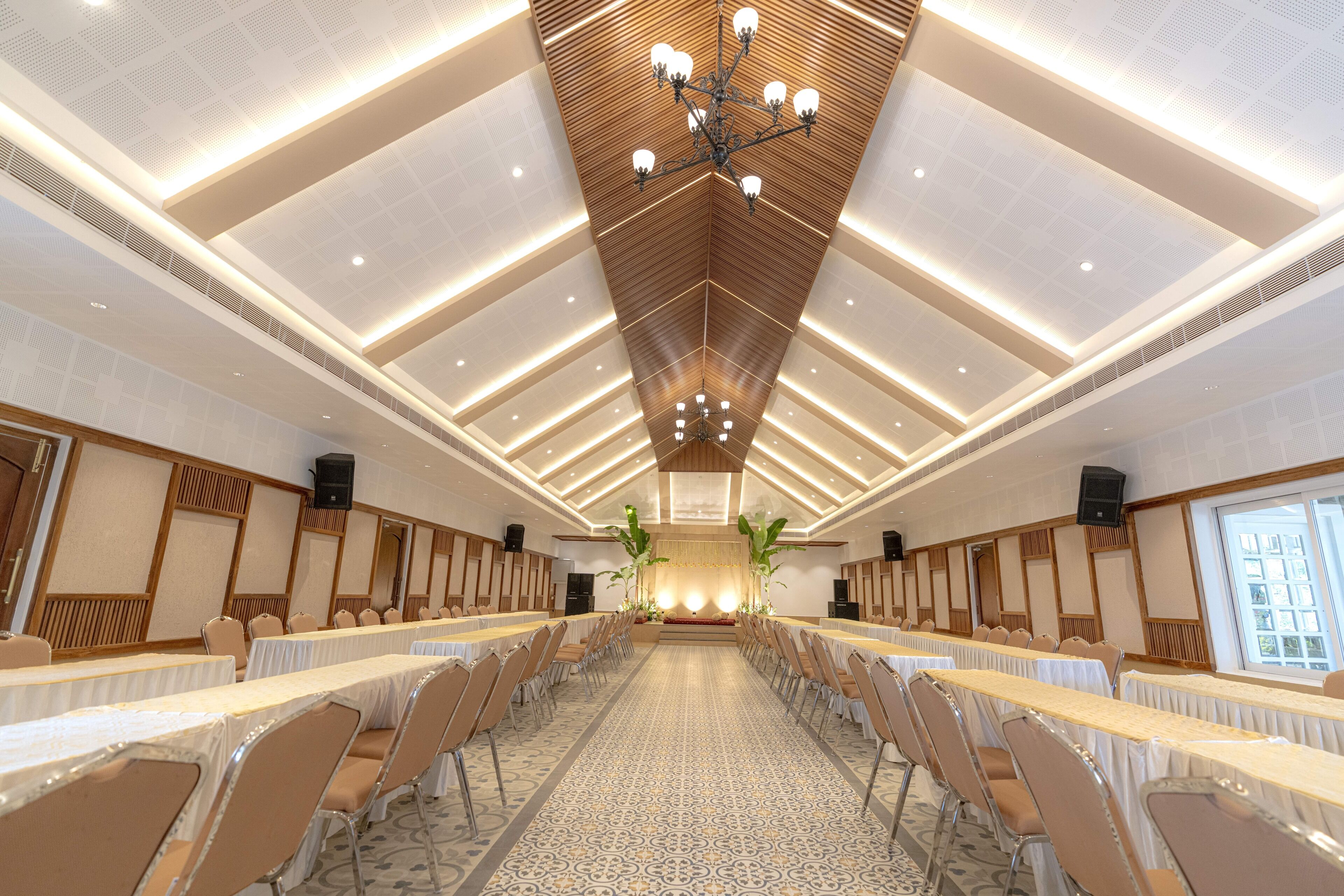 A conference room with long tables, chairs, and a high ceiling with a wooden panel design.