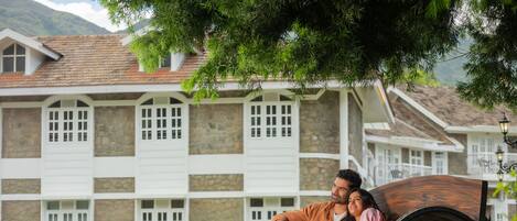 A couple sitting on a wooden bench with a stone building in the background.