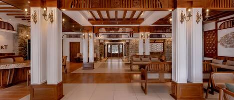 A spacious lobby with wooden beams, a stone wall, and a patterned rug.