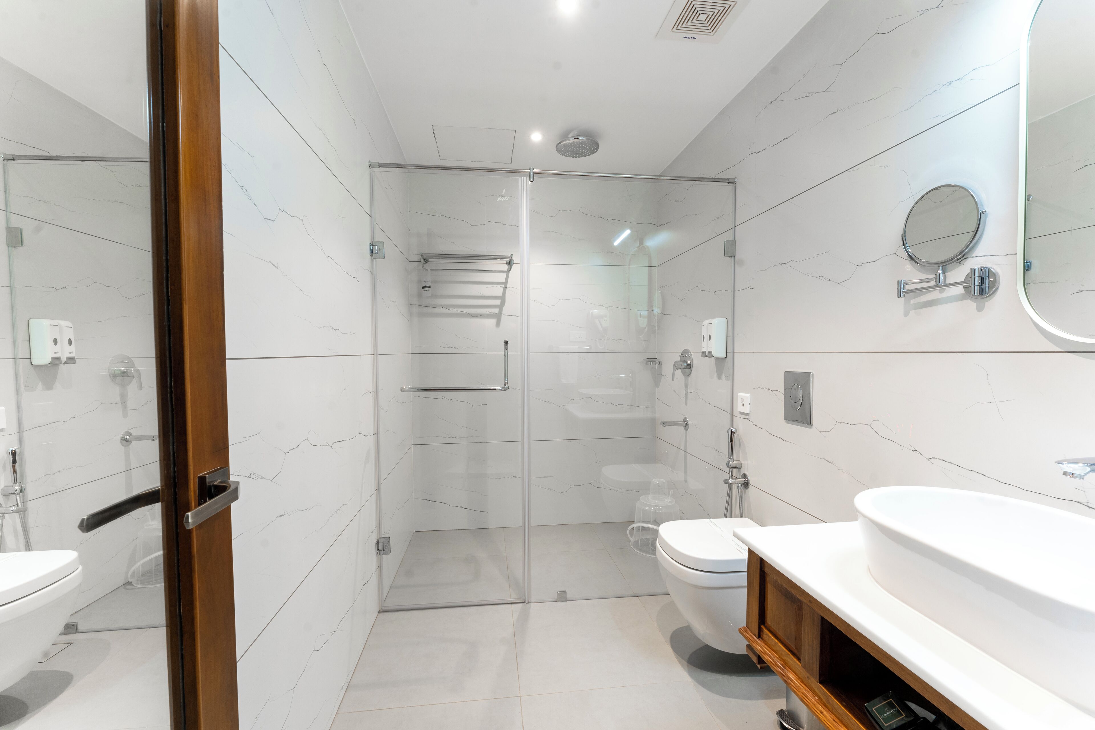 A modern bathroom with a glass-enclosed shower, a white toilet, and a vanity with a mirror.