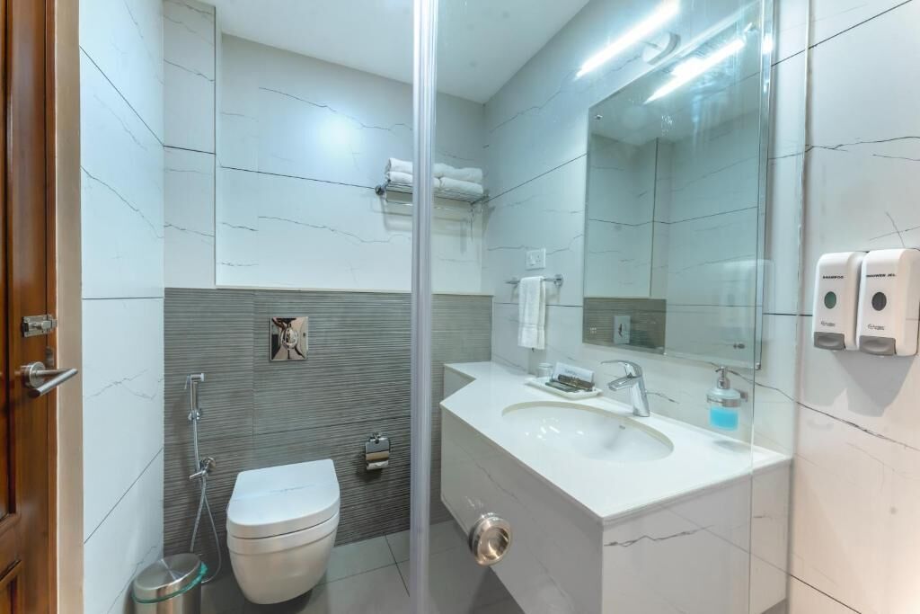 A modern bathroom with a glass shower enclosure, a white sink, and a toilet.