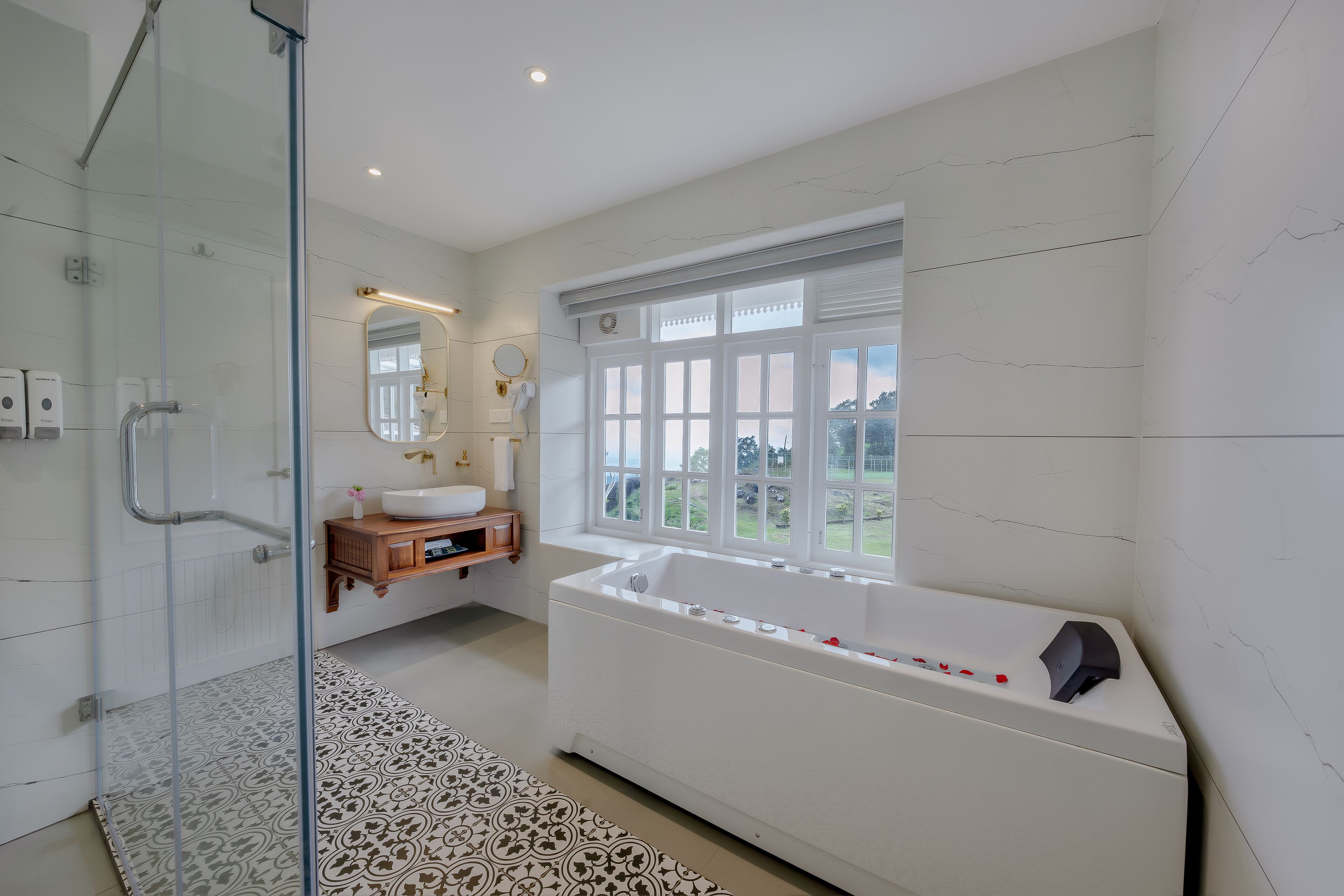 A modern bathroom with a glass shower enclosure, a freestanding bathtub, and a large window providing a view of the outdoors.