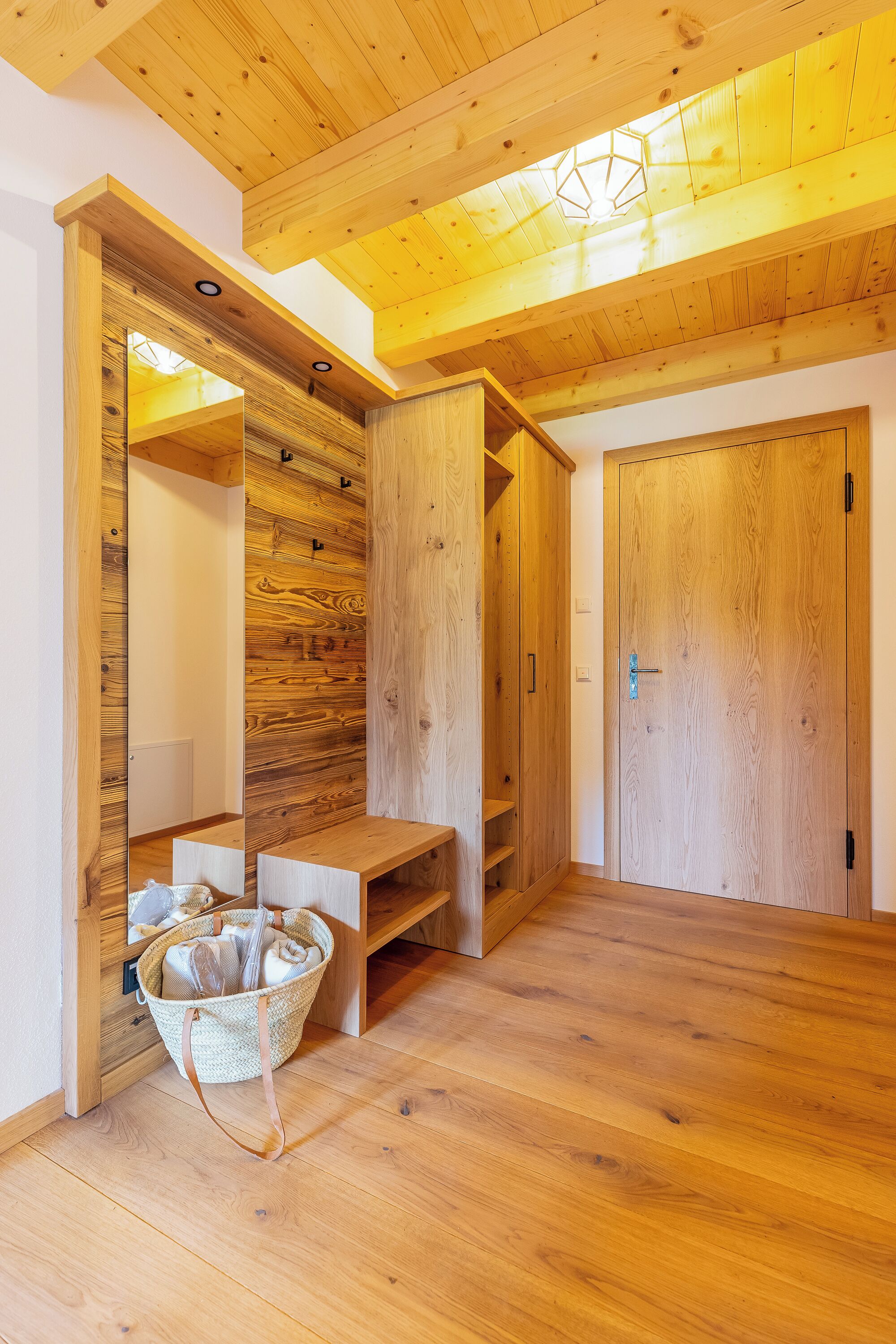 A wooden interior with a bench, a basket, and a door.