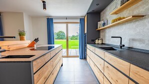 Eine moderne Küche mit Holzschränken, einer integrierten Kochinsel und einem großen Fenster mit blauen Vorhängen.