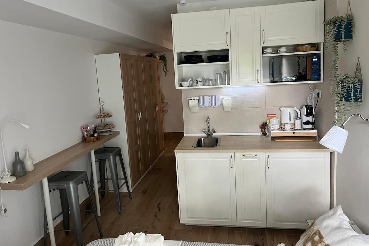 A compact kitchen with white cabinets, a microwave, a sink, and a small bar area with stools.