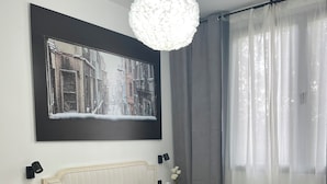 A neatly arranged bedroom with a bed, bedside tables, a hanging light fixture, and a large framed picture on the wall. - GARDEN HOUSE MADRID (Madrid)