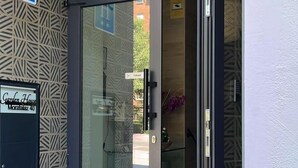A modern building entrance with a glass door, a sign reading "Garden House," and a blue sign with an 'H' indicating a hotel. - GARDEN HOUSE MADRID (Madrid)