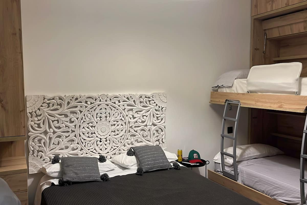A bunk bed with a ladder, a headboard with intricate carvings, and a small bedside table with a can and a cap.