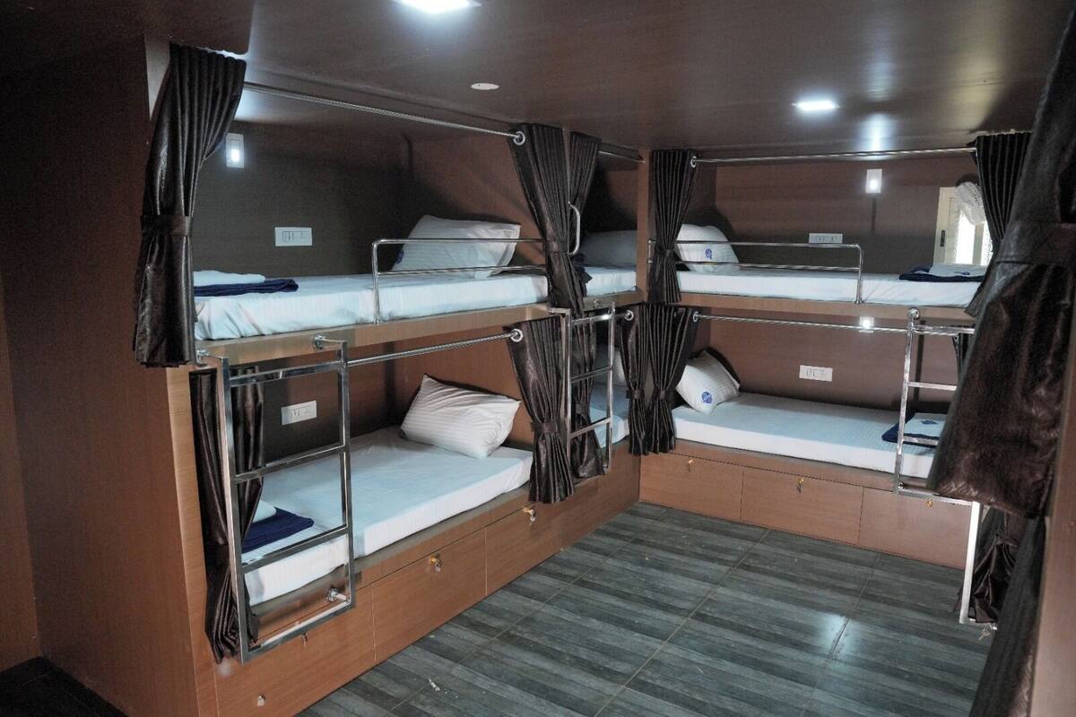 A train compartment with bunk beds, curtains, and a small storage area.