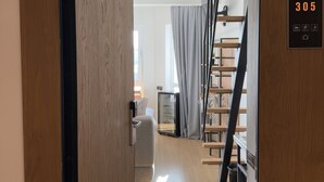 Een moderne hotelkamer met een houten vloer, een bed, een bureau en een trap.