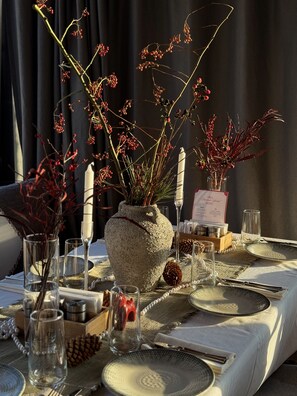 A table set for a meal with a stone vase centerpiece, clear glasses, and a menu sign. - Mosh Mosh Boutique Hotel (Almaty)