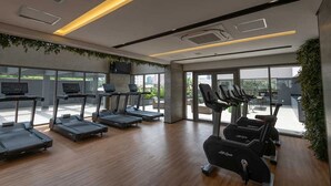 A modern gym with treadmills, stationary bikes, and a weight bench.