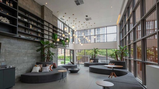 A modern lounge area with curved seating, a coffee table, and a bookshelf.
