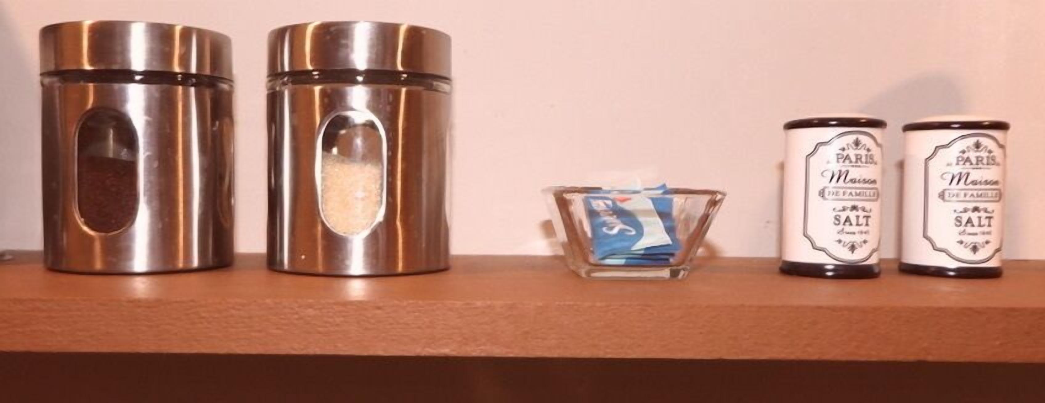 Two stainless steel containers, a small glass jar, and two white cans with labels.