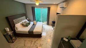 Una habitación de hotel con cama, mesita de noche, escritorio, silla y baño.