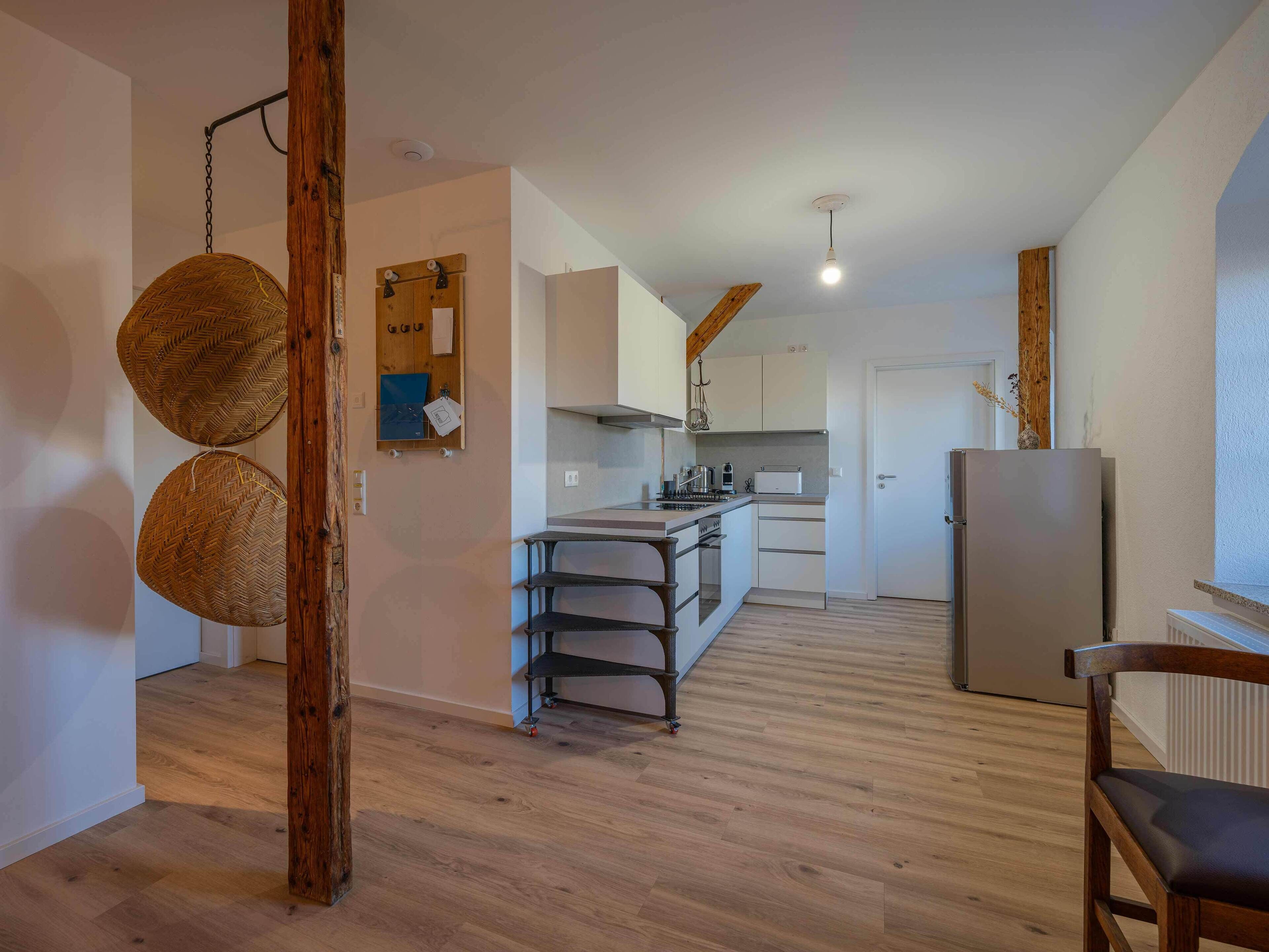 Une cuisine moderne avec des meubles blancs, un réfrigérateur en acier inoxydable et une table à manger en bois.