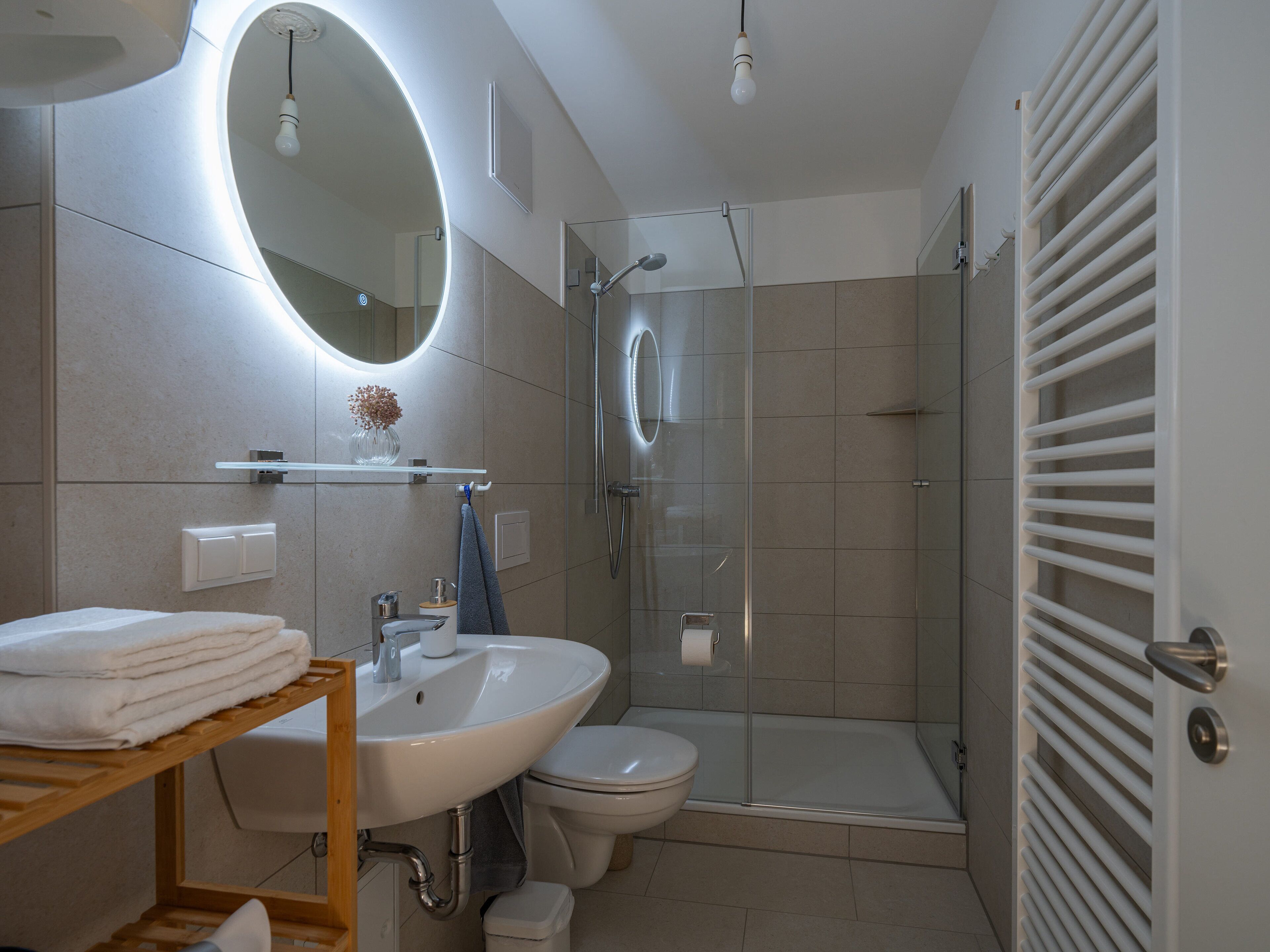 A modern bathroom with a sink, toilet, and glass-enclosed shower.
