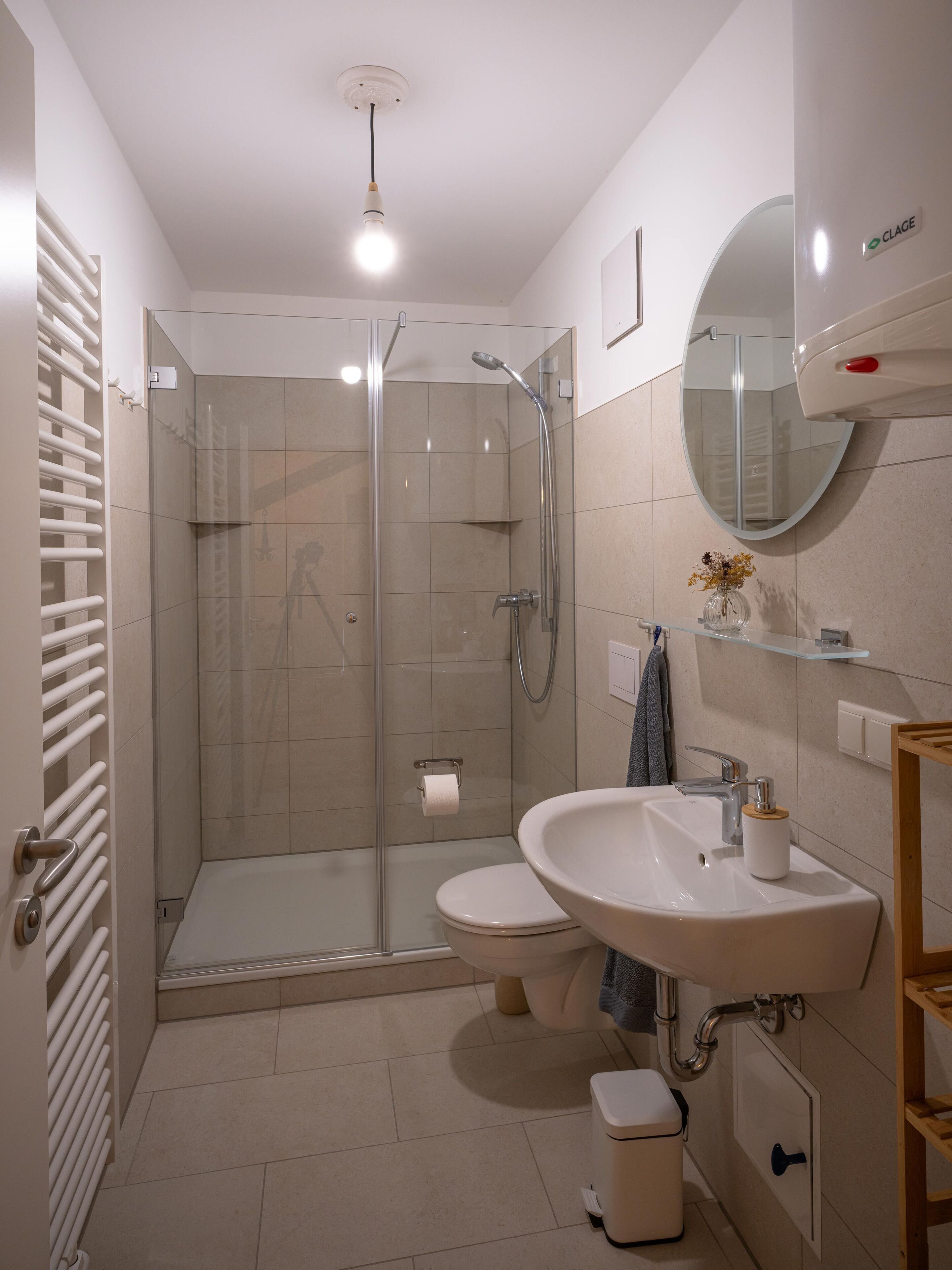 A modern bathroom with a glass-enclosed shower, a white sink, and a mirror.
