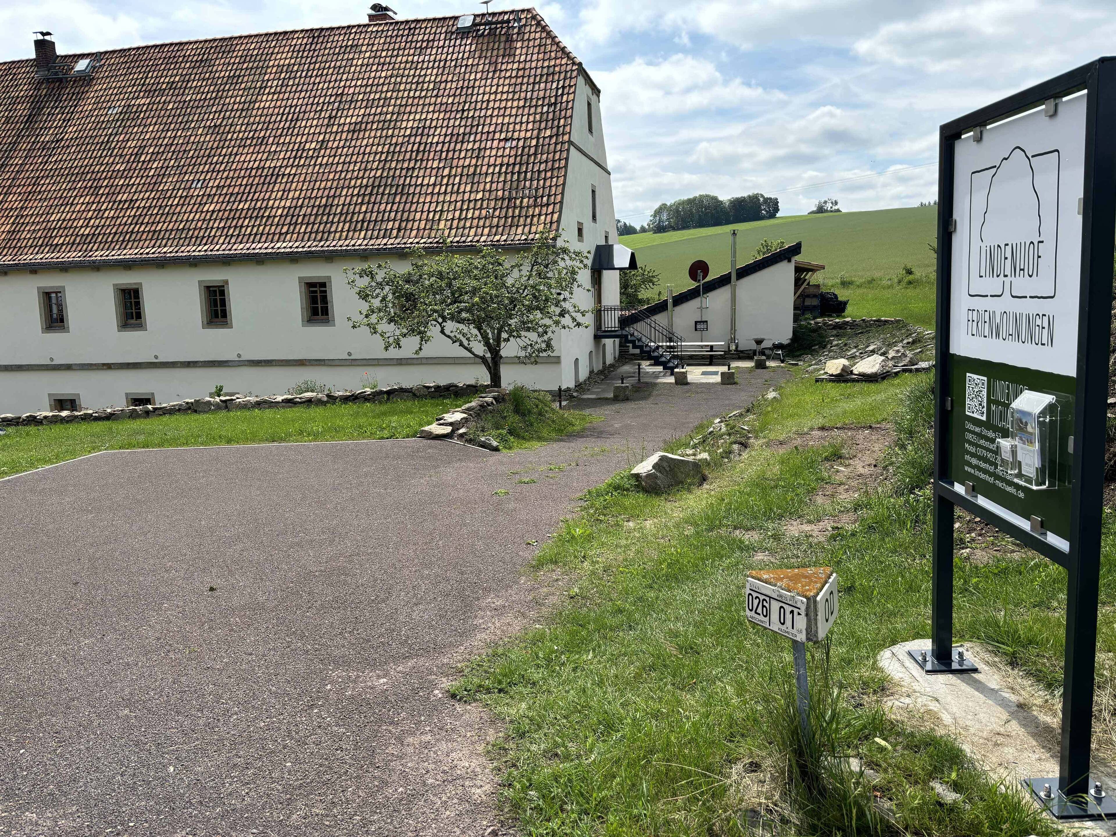 A building with a tiled roof and a signboard advertising 'Lindenhof Ferienwohnungen'.