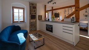 Une cuisine moderne avec un îlot central, des poutres en bois et un mur en pierre rustique.