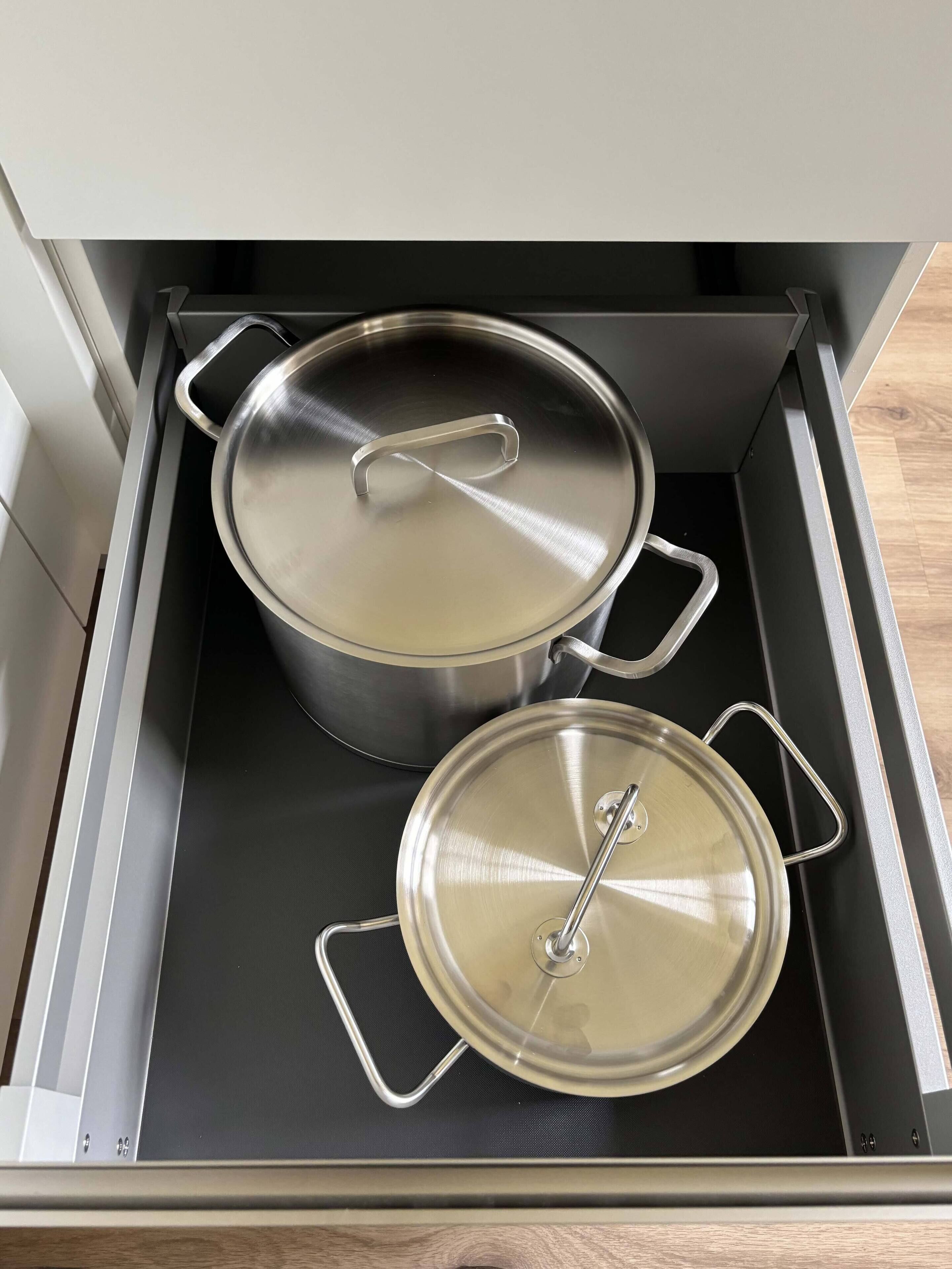 A stainless steel pot and pan set inside a drawer.