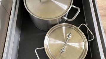 A stainless steel pot and pan set inside a drawer.