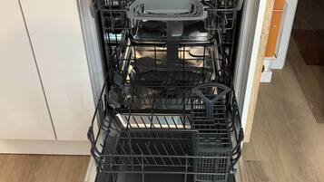 An open dishwasher with multiple racks and a control panel.