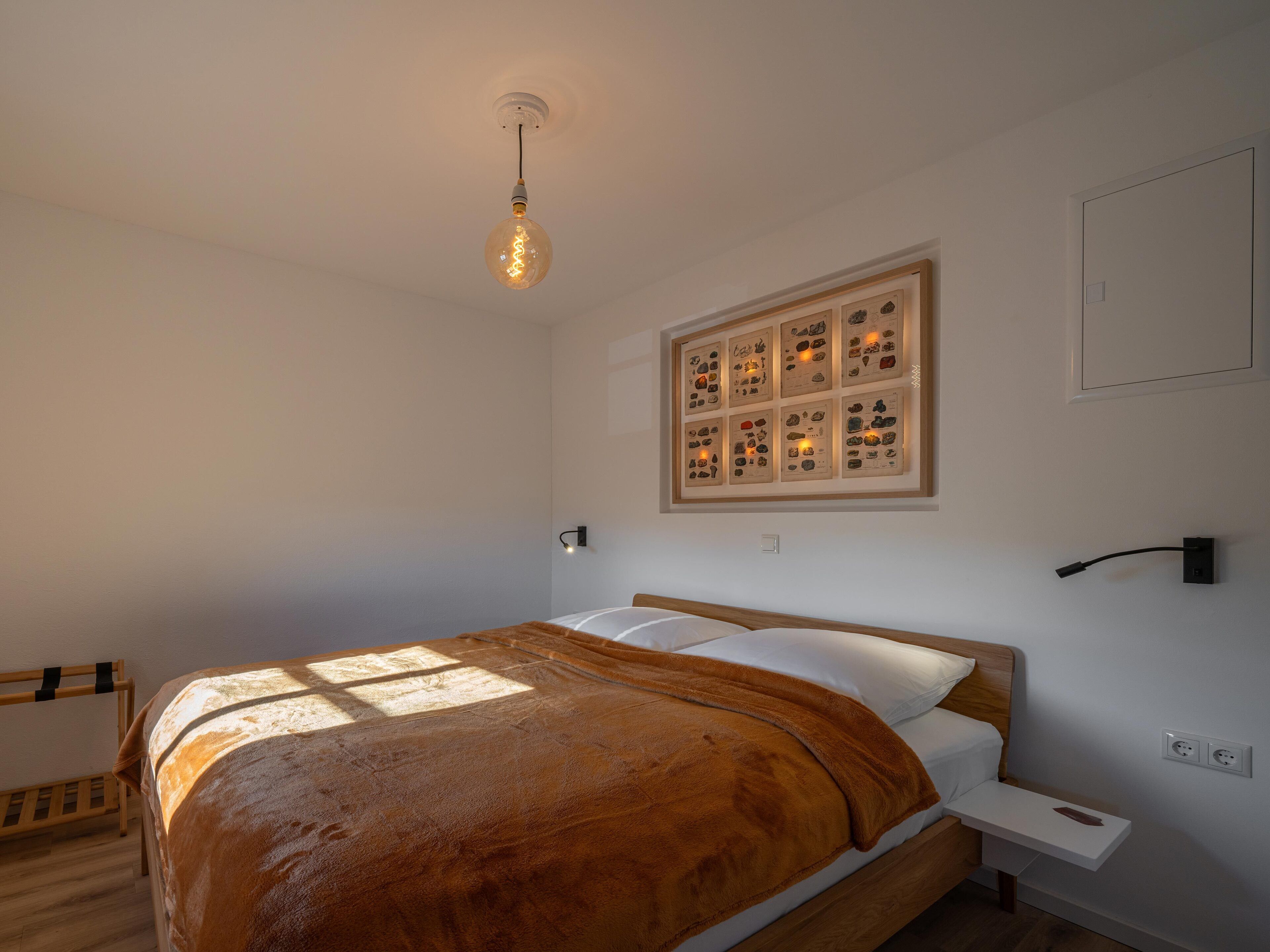 Une chambre à coucher comprenant un lit, une table de chevet, une étagère fixée au mur et une collection d’objets encadrés accrochés au mur.