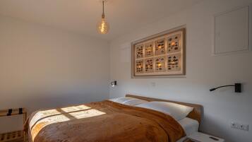 Une chambre à coucher comprenant un lit, une table de chevet, une étagère fixée au mur et une collection d’objets encadrés accrochés au mur.