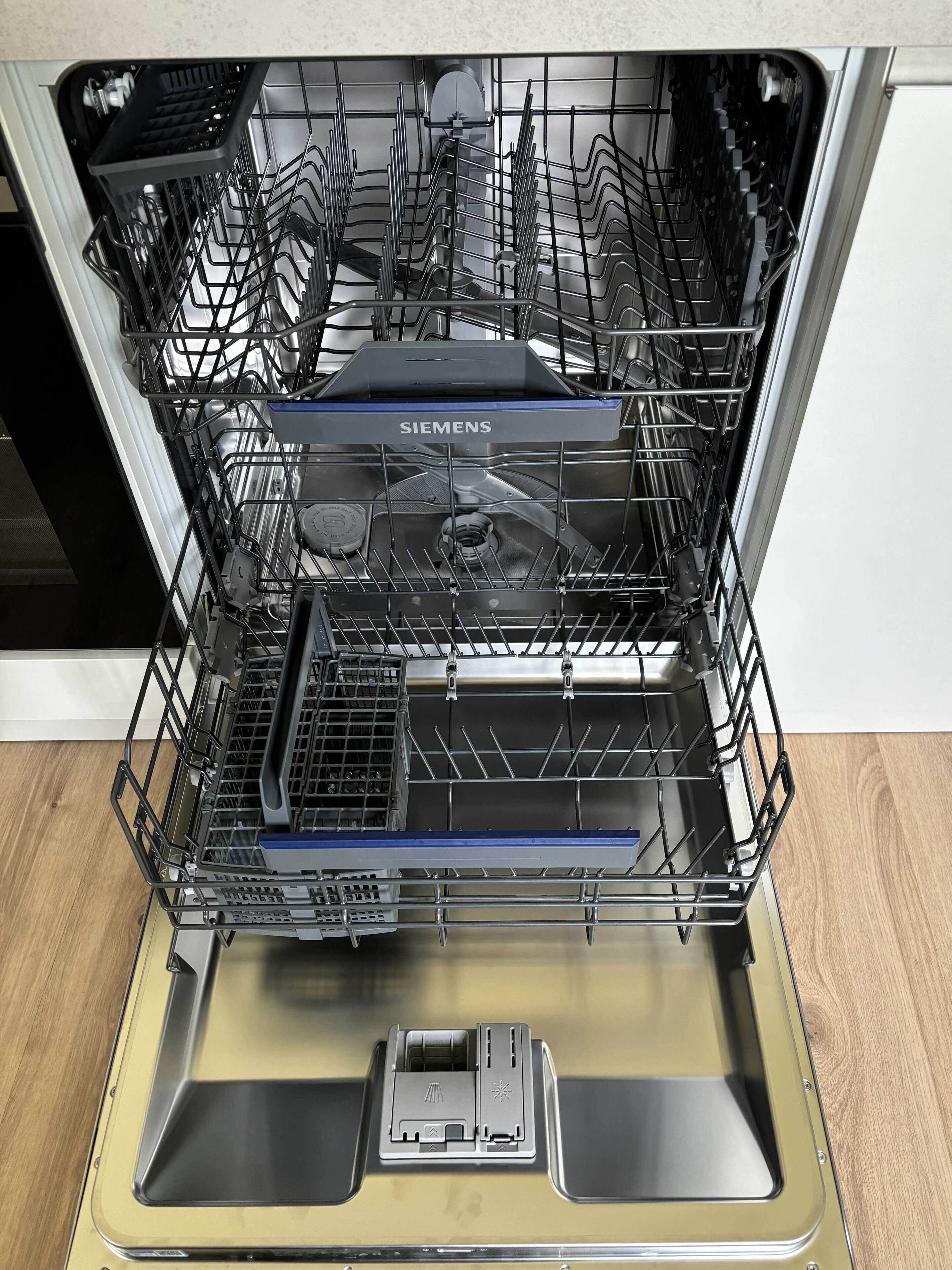 An open dishwasher with multiple racks and a control panel.