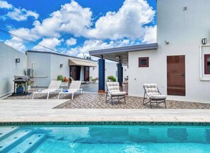 Una zona de piscina exterior moderna amb gandules i un porxo cobert.