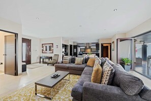 A modern living room with a sectional sofa, a coffee table, and a dining area with chairs.