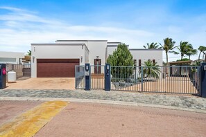 Zona residencial tancada amb una casa moderna, un garatge i un camí d'accés pavimentat.