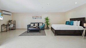 Een moderne slaapkamer met een groot bed, een bank, een salontafel en een bureau met stoel.