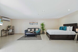 A modern bedroom with a large bed, a sofa, a coffee table, and a desk with a chair. - Private Pool Oasis! Secluded 4BR w Patio & Parking (Santa Cruz)