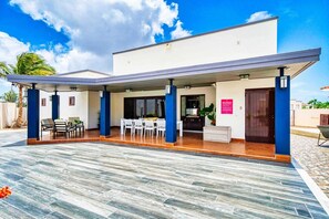 A modern building with a covered patio area, a dining setup, and a reception desk.