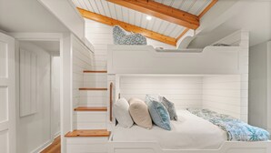A bunk bed with a wooden staircase and a sloped ceiling.