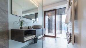 Ein modernes Badezimmer mit großem Spiegel, integrierten Ablagen, einem Steintonne und einem Blumentopf.