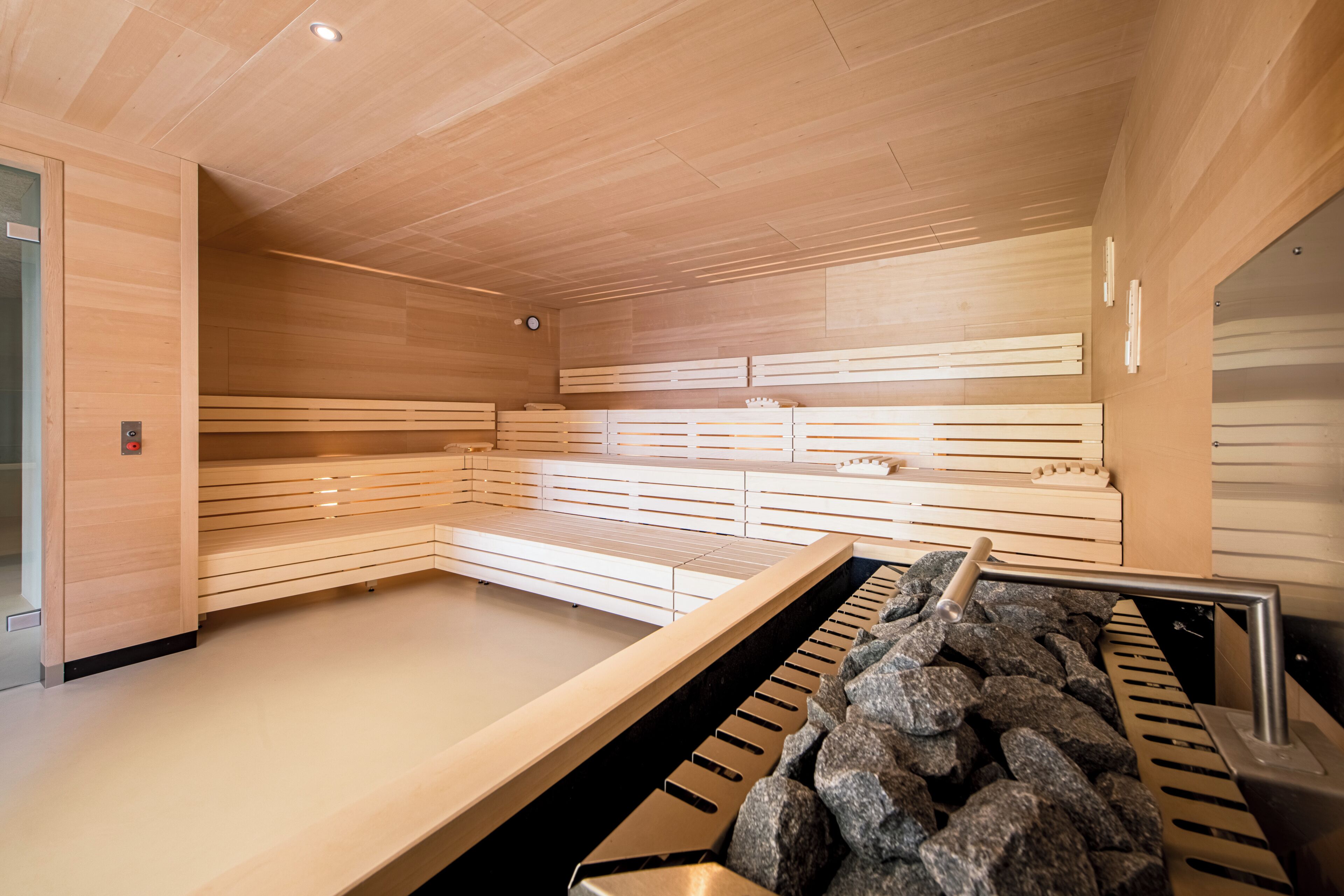 A sauna room with wooden benches and a stone basin.