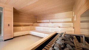 Ein modernes Saunabadezimmer mit Holzsitzen und einer Steinwand.