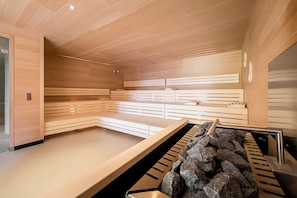 Ein modernes Saunabadezimmer mit Holzsitzen und einer Steinwand.
