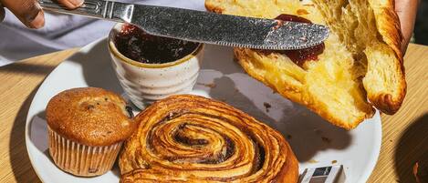 A plate with a muffin, a cinnamon roll, and a piece of bread with jam.