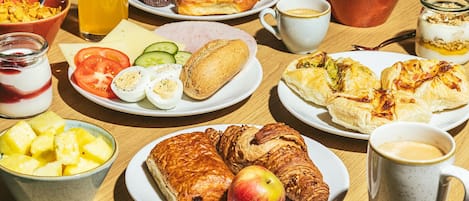 Een ontbijttafel met diverse etenswaren, zoals croissants, eieren en fruit.